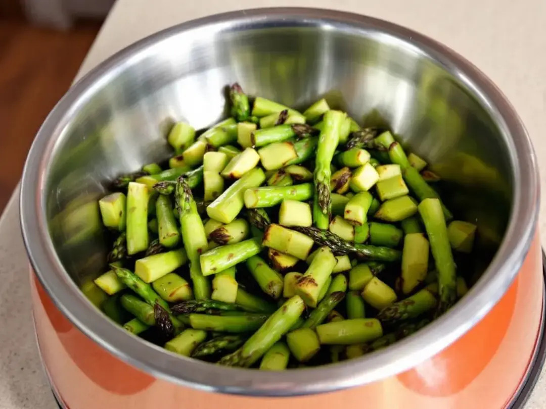 In the image, properly cooked asparagus is cut into small bite-sized pieces and placed in a dog bowl, showcasing a...