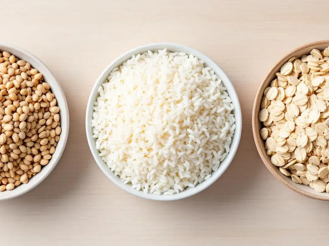 In this image, there are three separate bowls containing different grains: barley, rice, and oats, arranged side by...