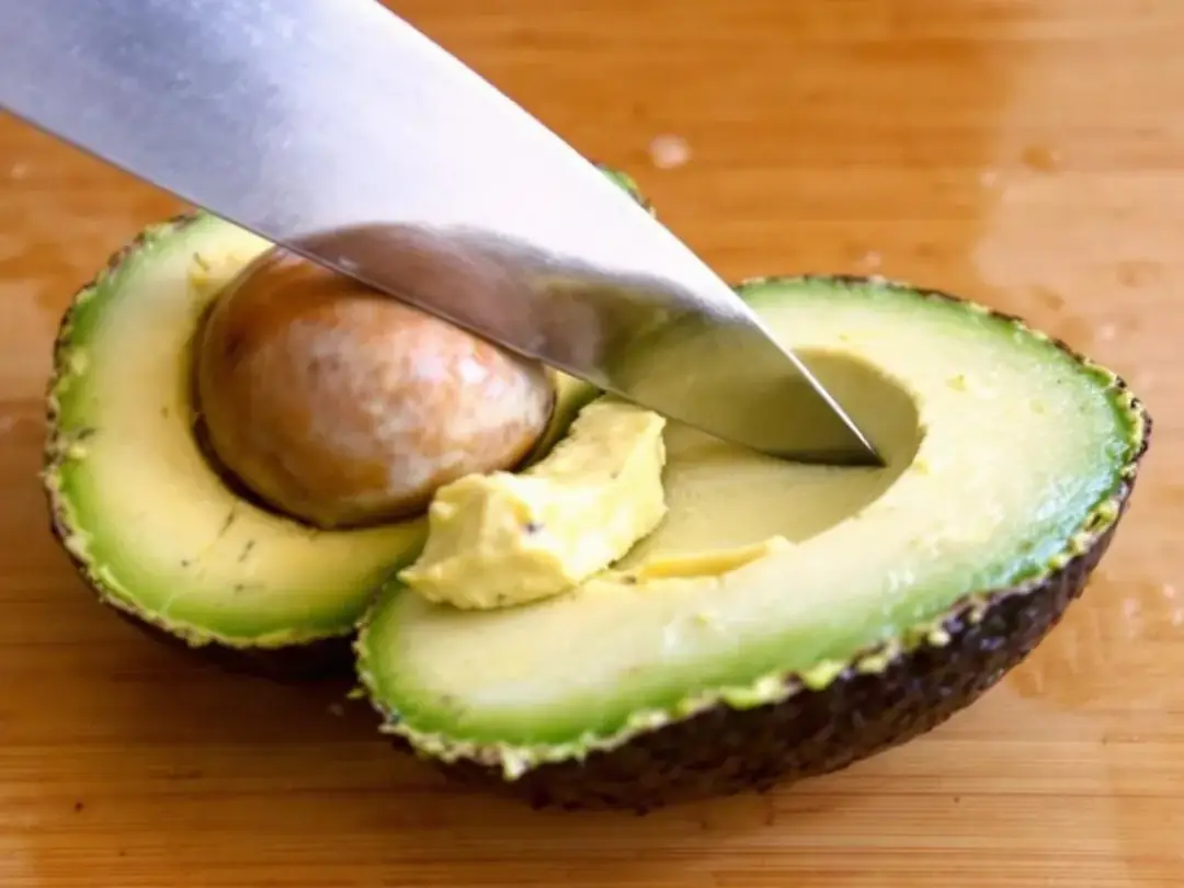 A close-up image shows creamy avocado flesh being carefully prepared, highlighting its rich texture and vibrant green...